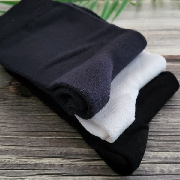 3 pairs of socks folded on wood table with green leaves